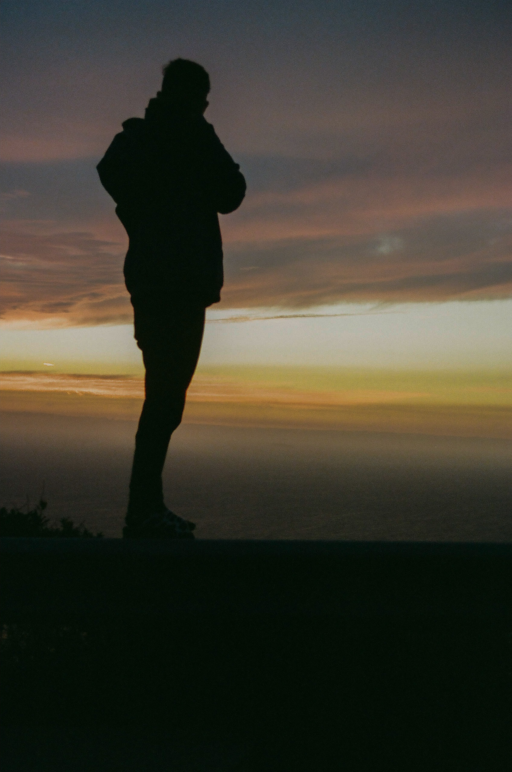 Silhouette of friend taking photo with sunset appearing behind him.