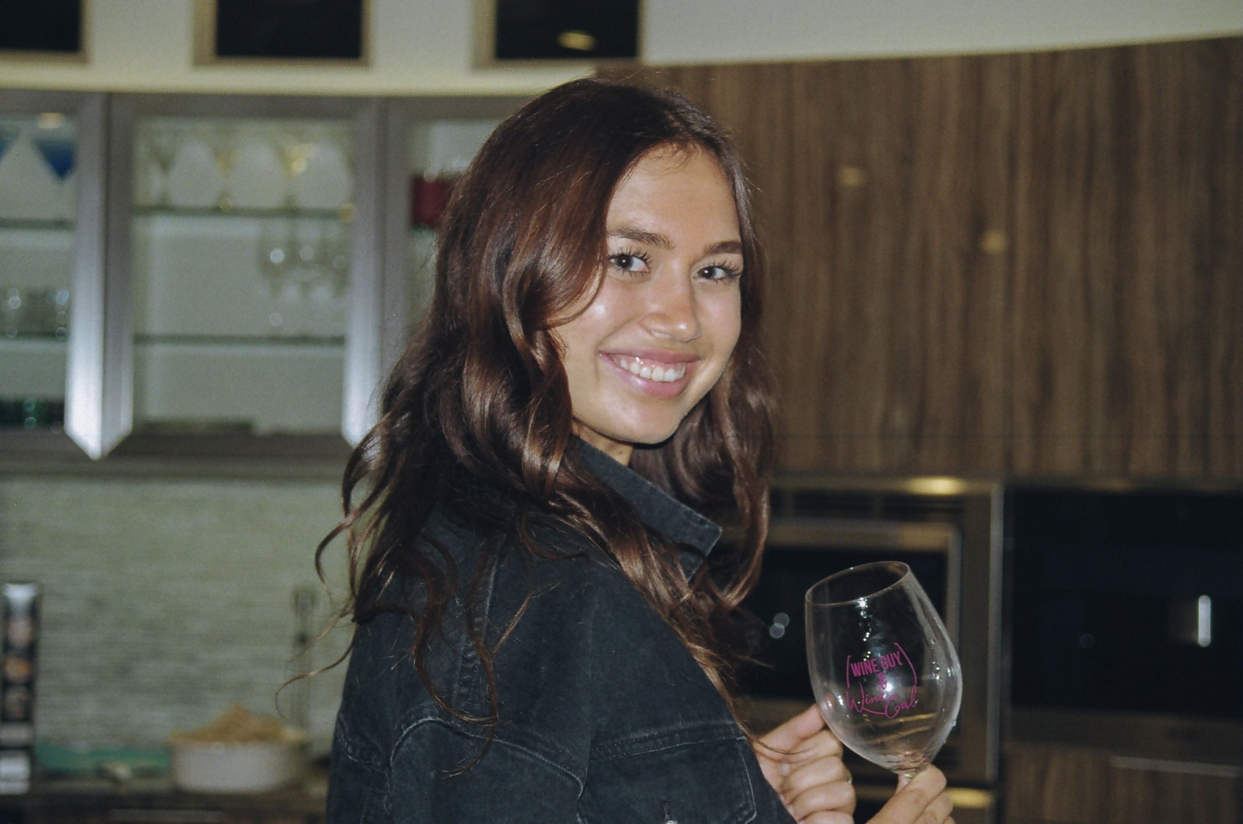 Friend smiles for a portrait shot with her wine glass in hand.