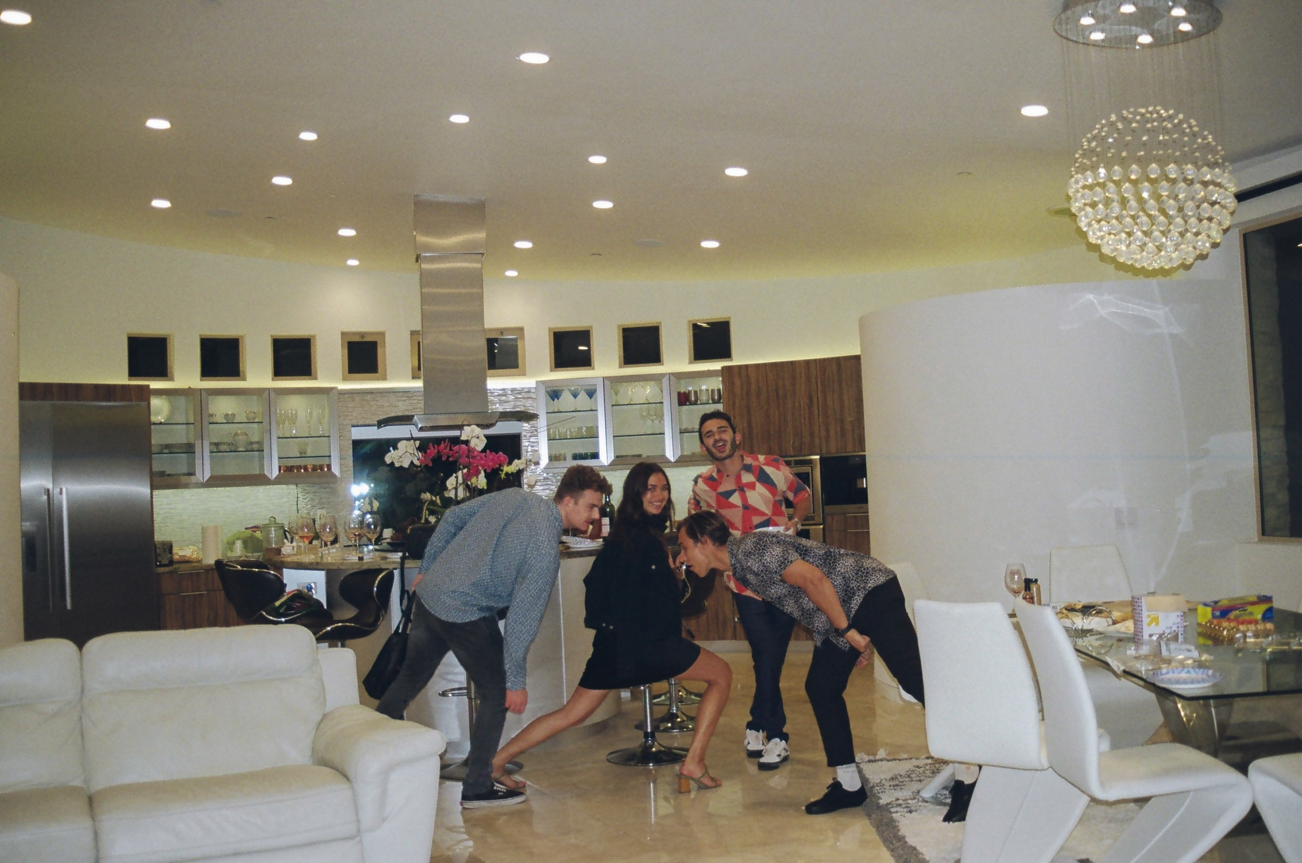 Four friends posing for a photo in a dining room.