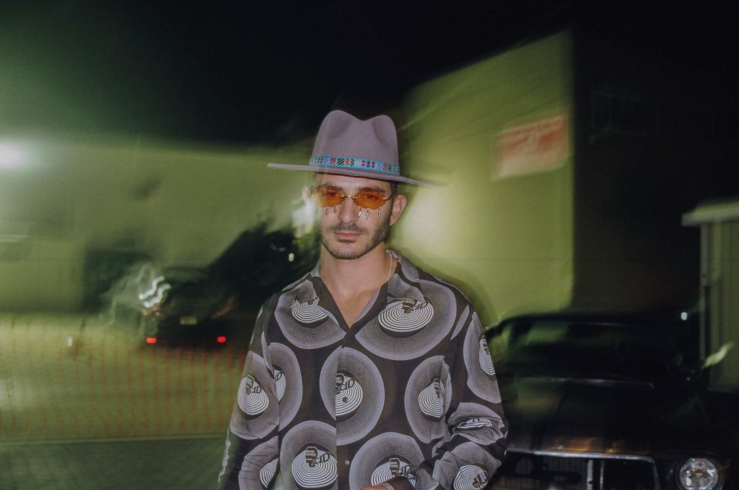 Friend poses for a picture in front of vintage car; image appears focused only around him while background is blurred.