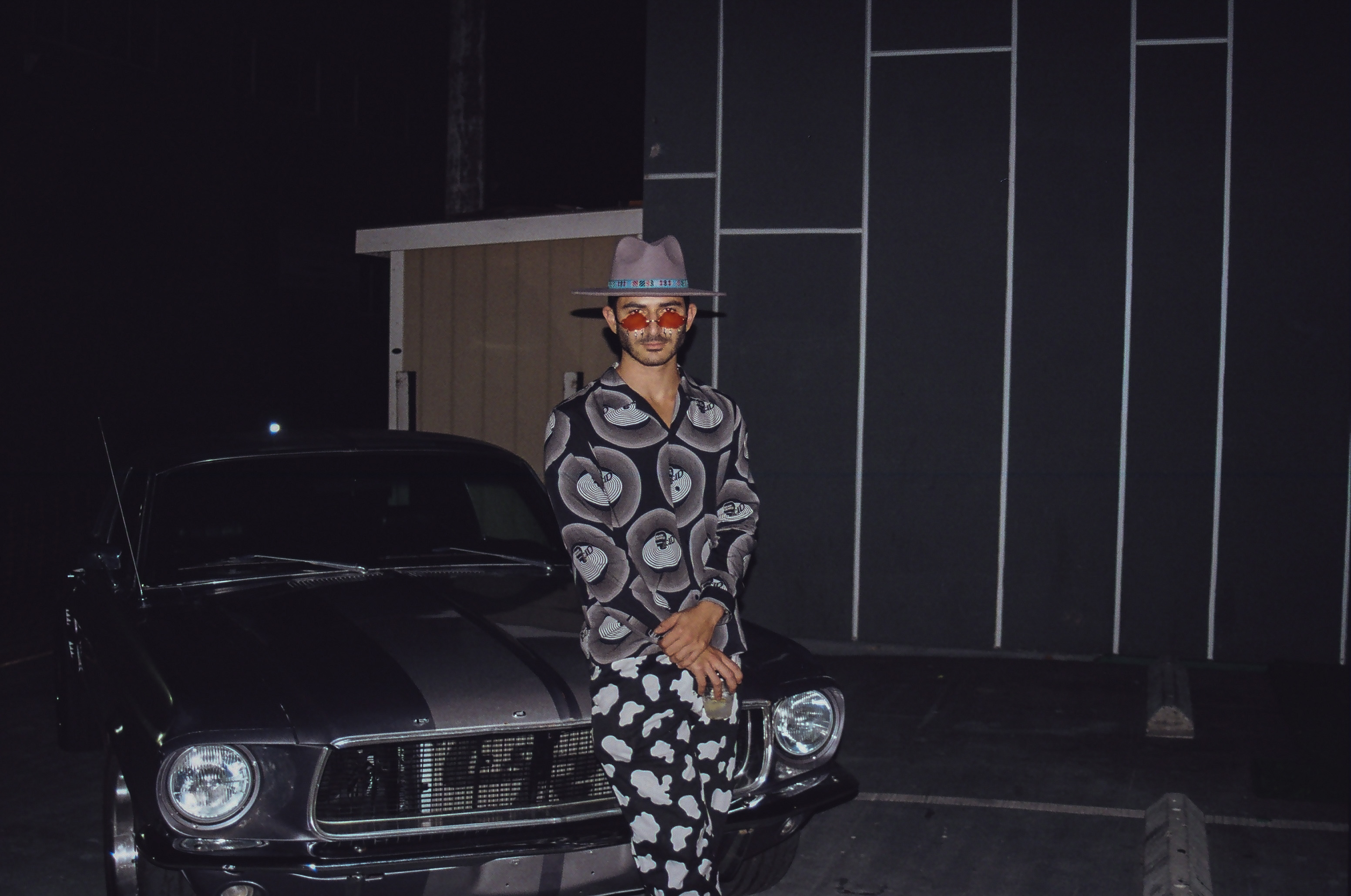 Friend poses for picture in front of vintage car.