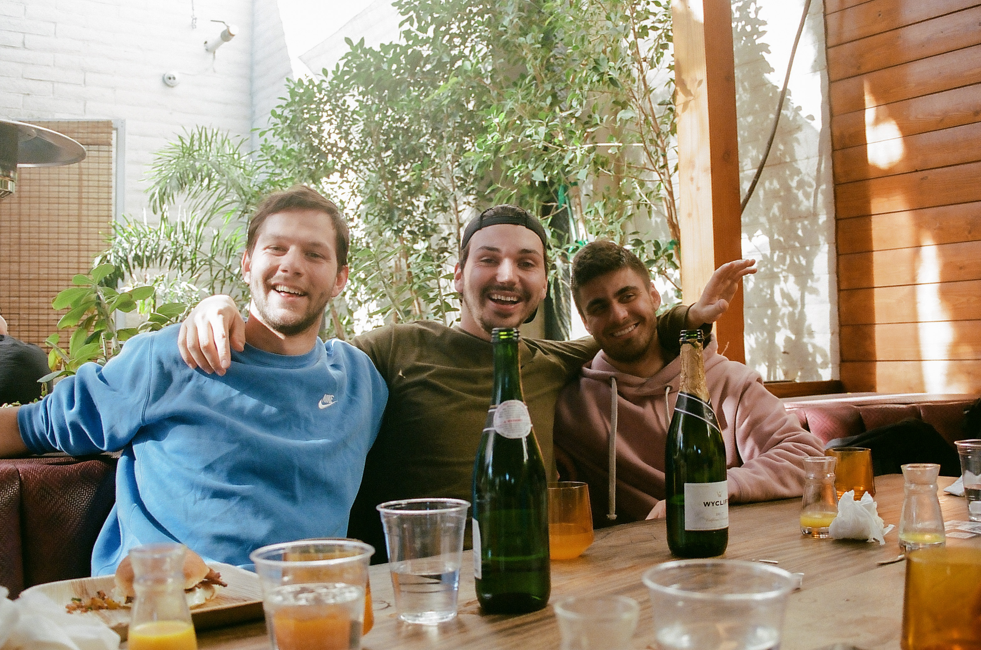 Three friends in a booth smile and pose for a photo during Sunday brunch at Sunbar in Tempe.