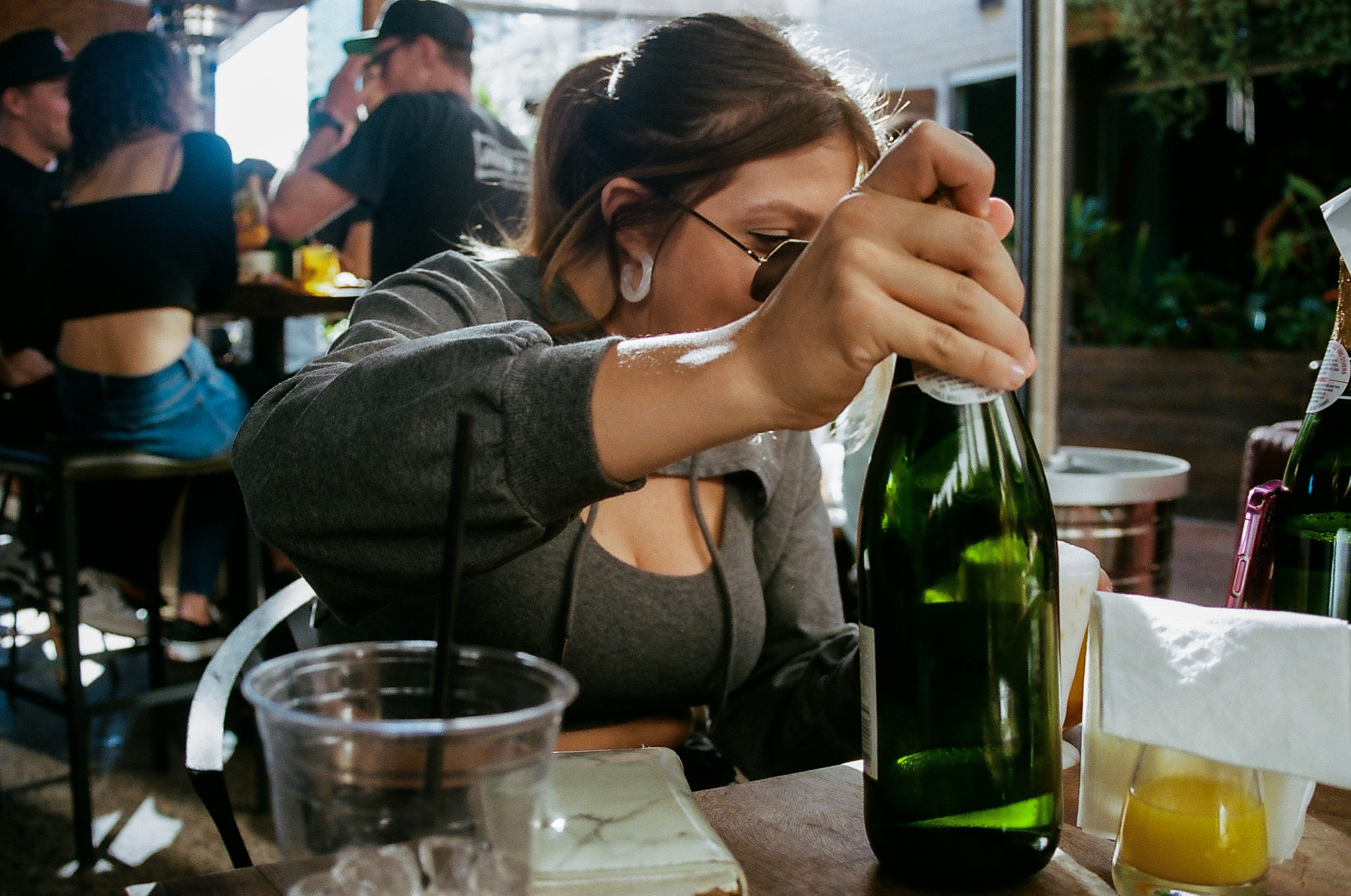 Friend grabs a bottle of champagne to make a mimosa during Sunday brunch at Sunbar in Tempe.