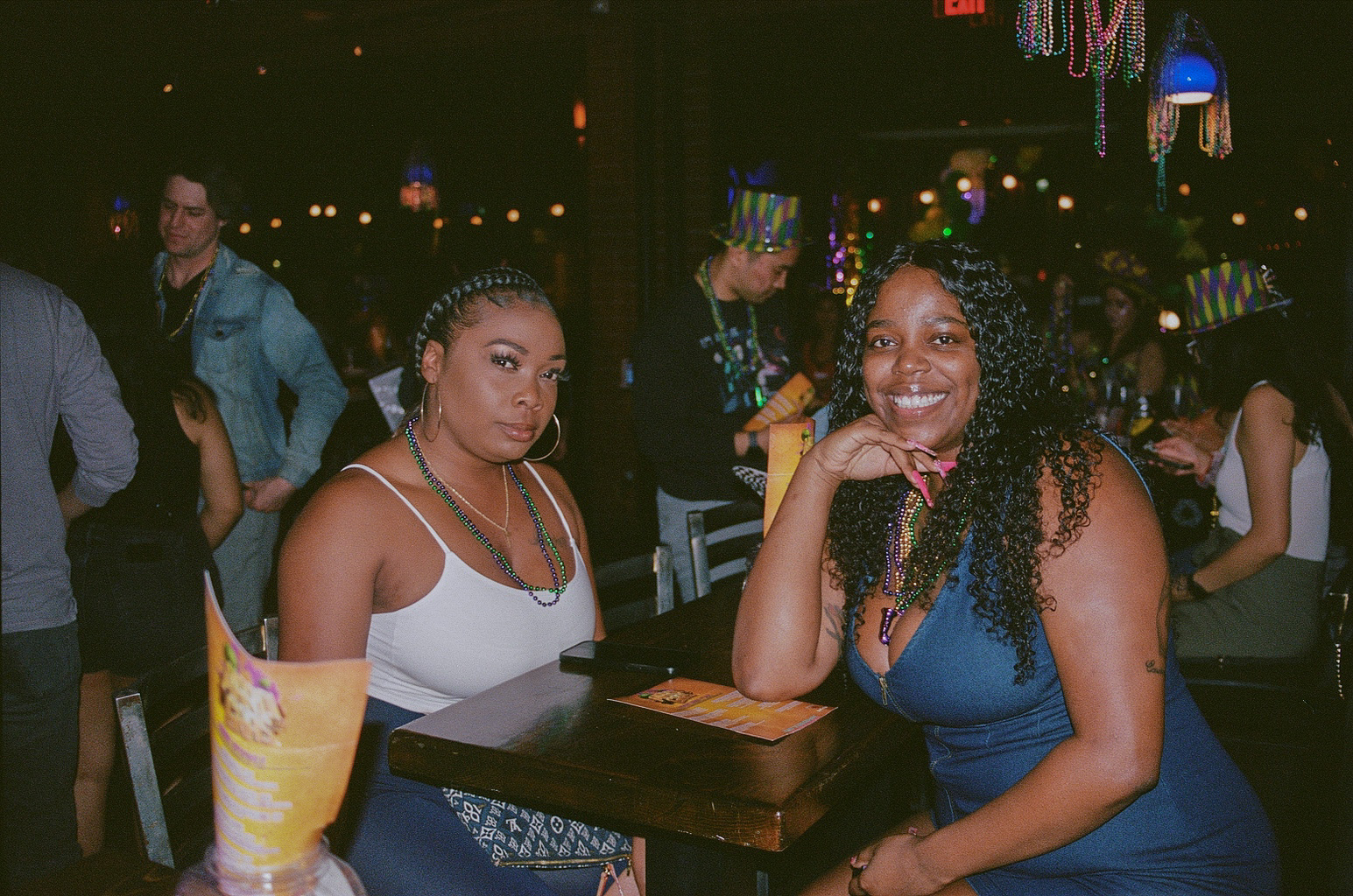 Two women smile and pose for a photo during Mardi Gras celebrations at Fat Tuesday on Mill Avenue in Downtown Tempe.