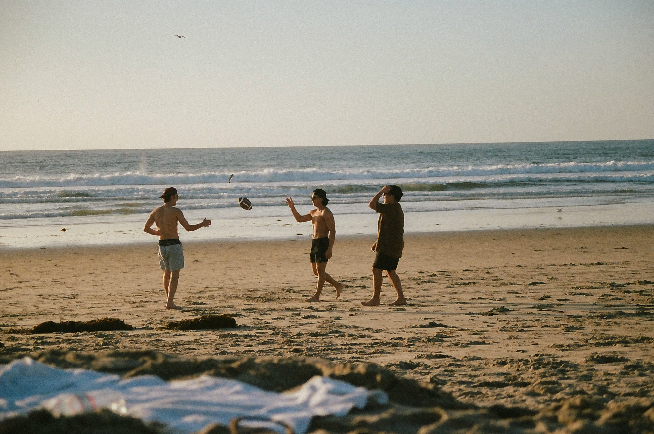 Three friends tossing around a football on the beach.