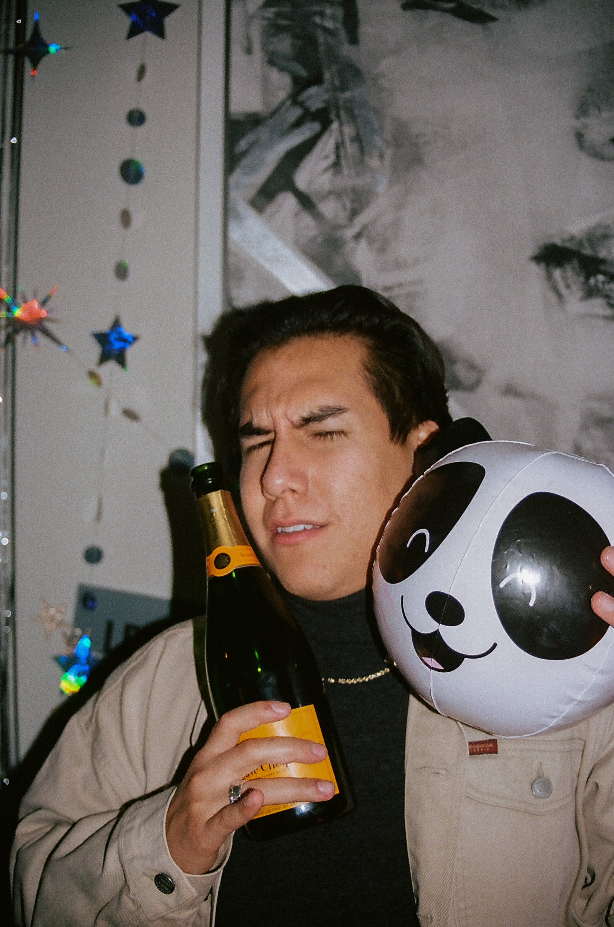 Friend poses for a picture with party decorations and champagne bottle.