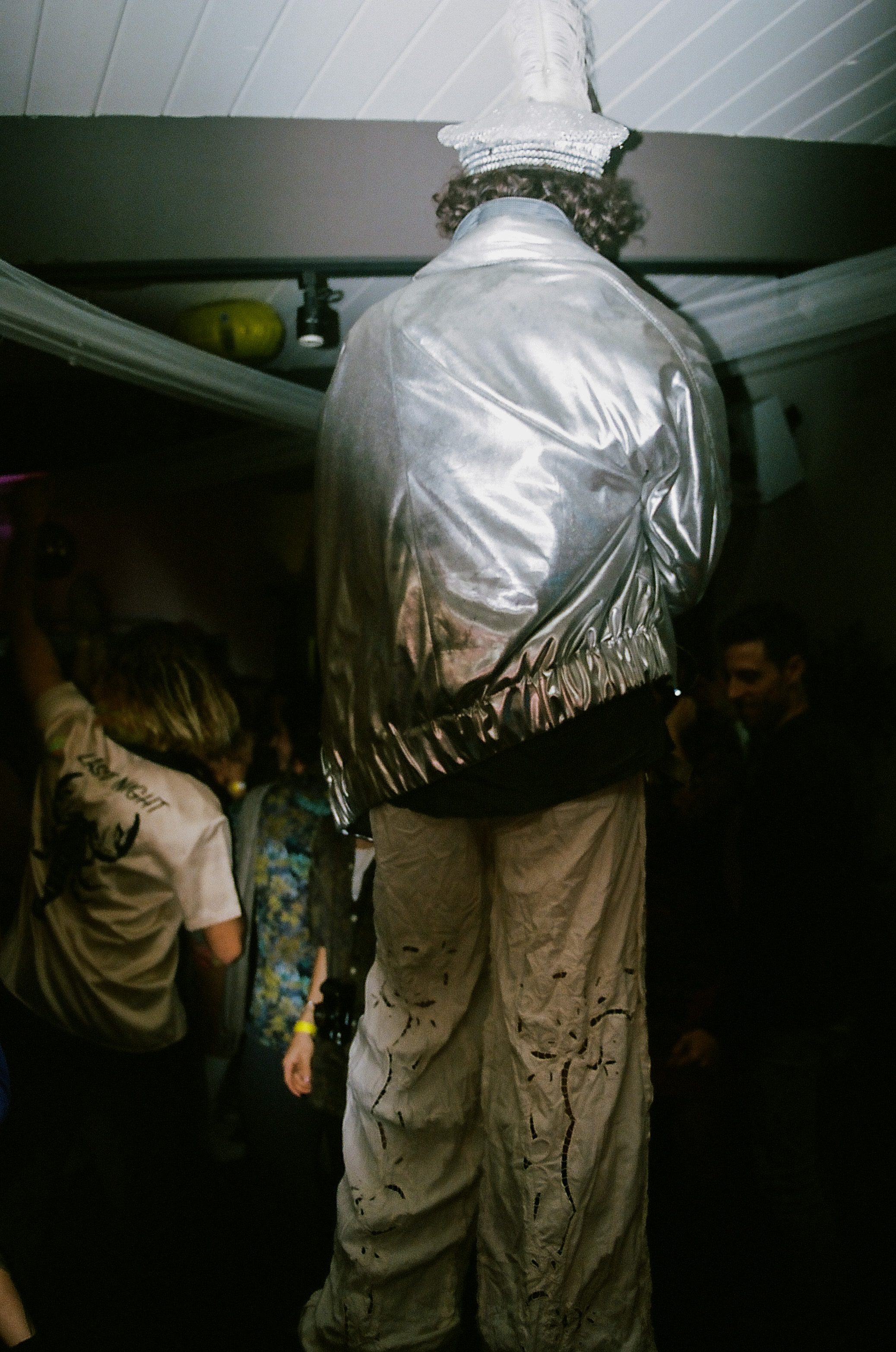 Man walks through dancefloor on stilts.