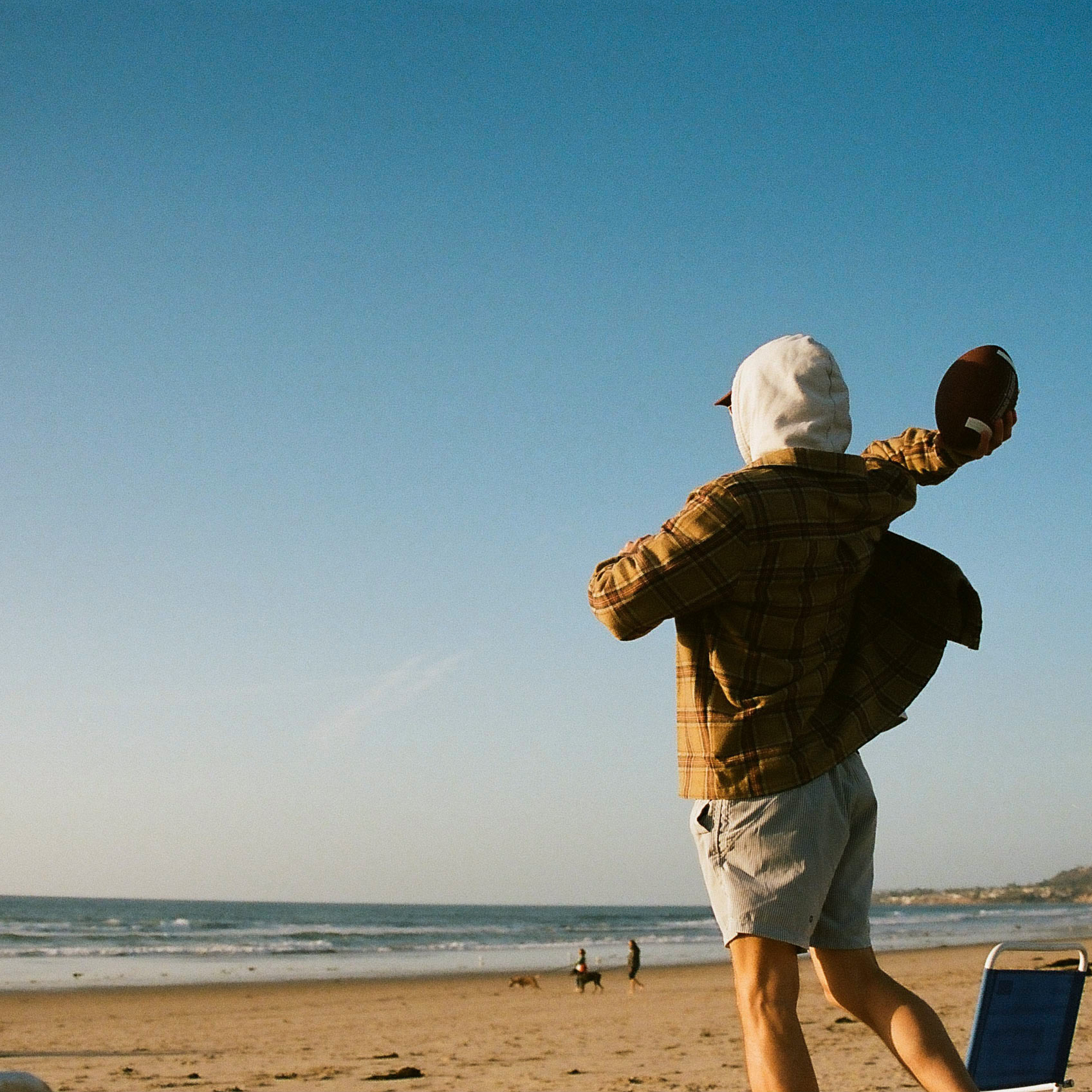 Friend throws football on the beach in San Diego.