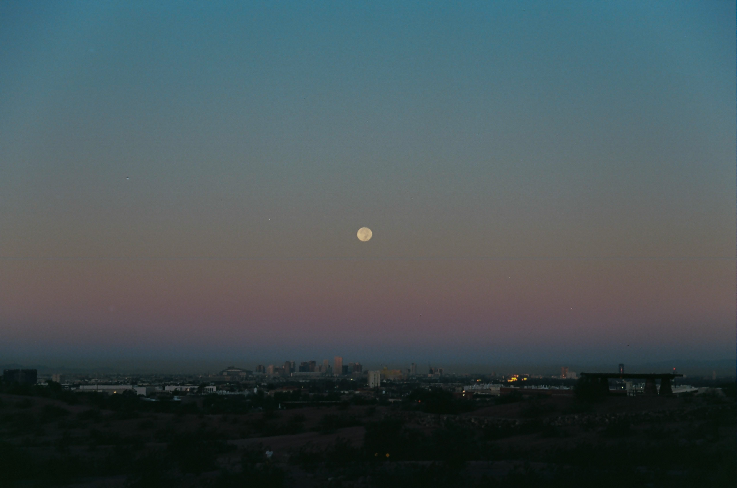 View from Papago Park of the moon resting above the city of Phoenix shortly after the sun sets.